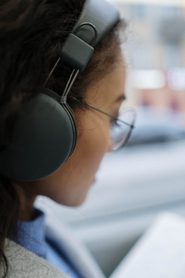 Een vrouw luistert met een koptelefoon op terwijl ze in een bus zit